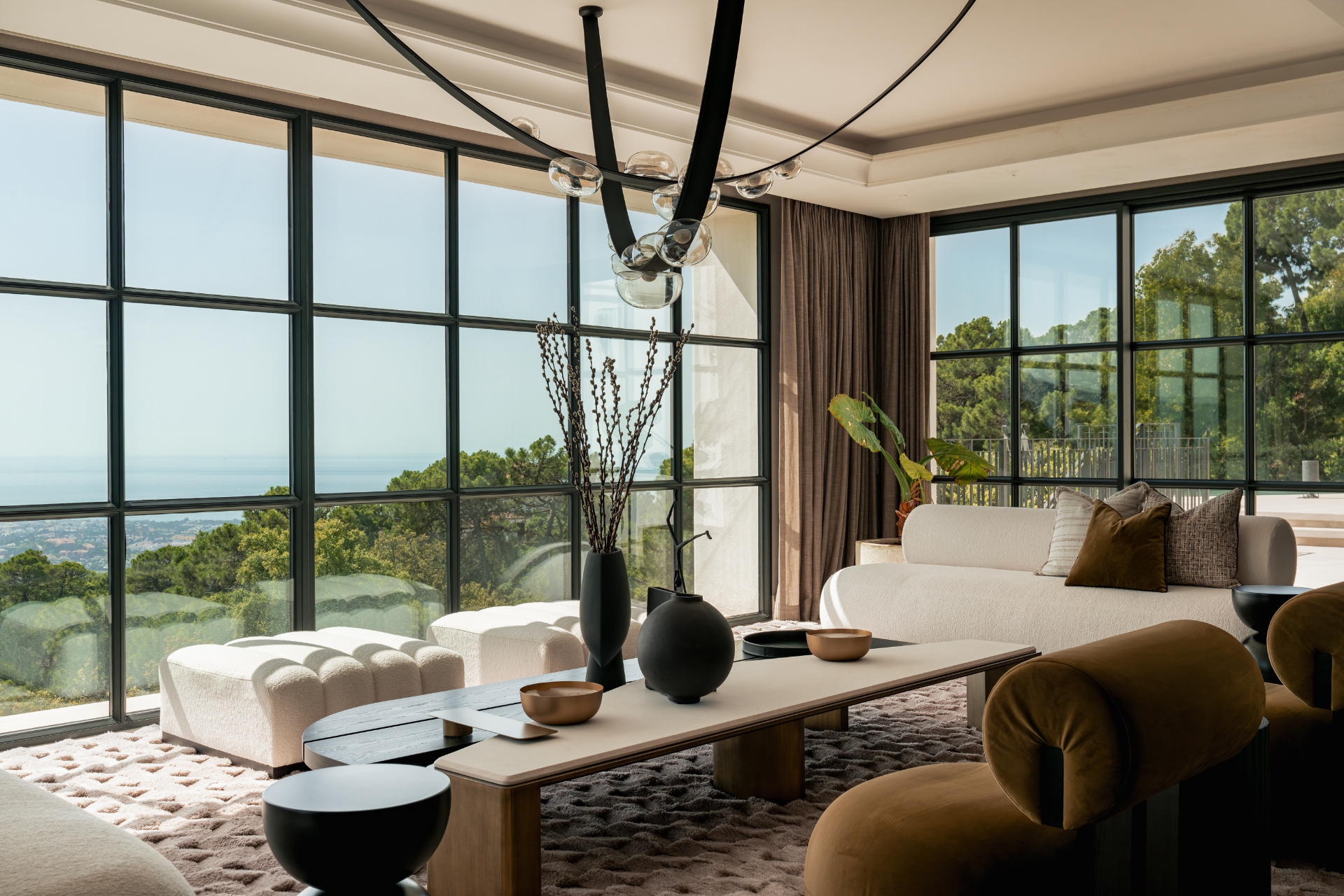 Living salon with steel-framed windows opening to the sea.
